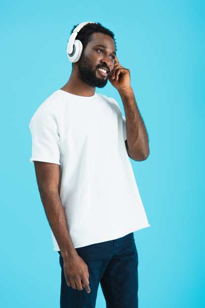 szczęśliwy African American Man słuchania muzyki ze słuchawkami, izolowane na niebiesko - Zdjęcie, obraz