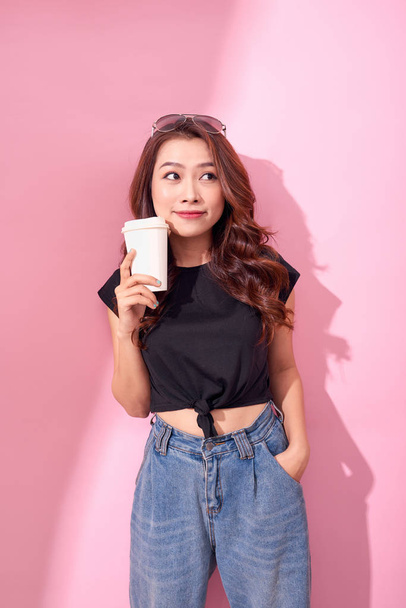 Fashion pretty woman with coffee cup wearing black  clothes over colorful pink background - Foto, imagen