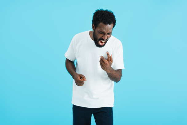 agressieve Afro-Amerikaanse man schreeuwen op smartphone, geïsoleerd op blauw - Foto, afbeelding