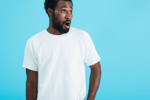 surprised african american man in white t-shirt, isolated on blue   - Foto, afbeelding