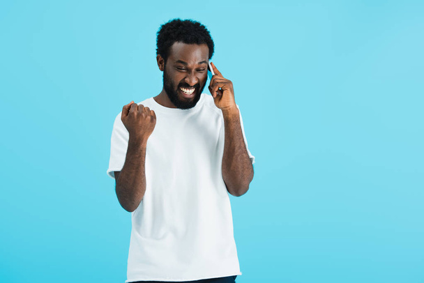 ενθουσιασμένος Αφρικανός Αμερικανός άνθρωπος μιλάει στο smartphone, απομονωμένη στο μπλε - Φωτογραφία, εικόνα
