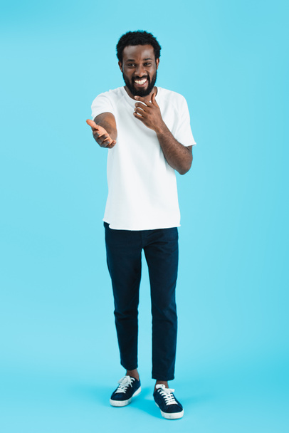 happy african american man laughing and gesturing isolated on blue - 写真・画像