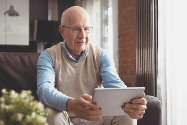 Senior man using digital tablet in living room - Foto, Imagen