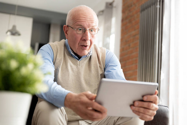 Smiling senior man using a digital tablet - Foto, Imagen