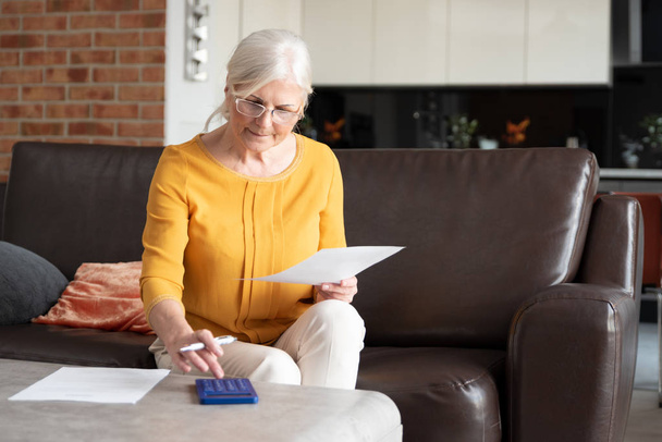 Senior woman with calculator and bills counting - Photo, Image