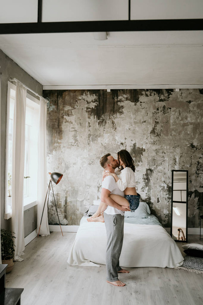 Couple in love in the bedroom. Slender brunette. Stylish interior. - Foto, Bild