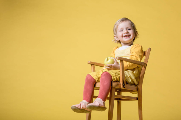 Młoda dziewczynka w żółtej sukience na żółtym tle - Zdjęcie, obraz