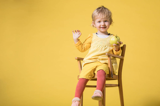 Mladé dítě dívka v žluté šaty na žlutém pozadí - Fotografie, Obrázek