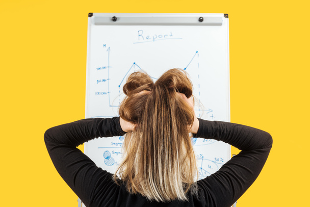 back view of businesswoman standing near white flipchart, holding hand on head - Photo, Image