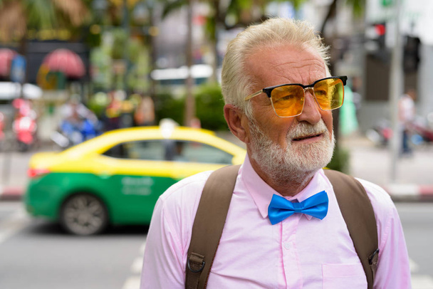 Portrait of handsome senior tourist man wearing stylish clothes while exploring the city of Bangkok, Thailand - 写真・画像