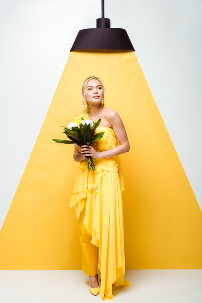 attractive young woman holding bouquet of flowers on white and yellow  - Fotoğraf, Görsel
