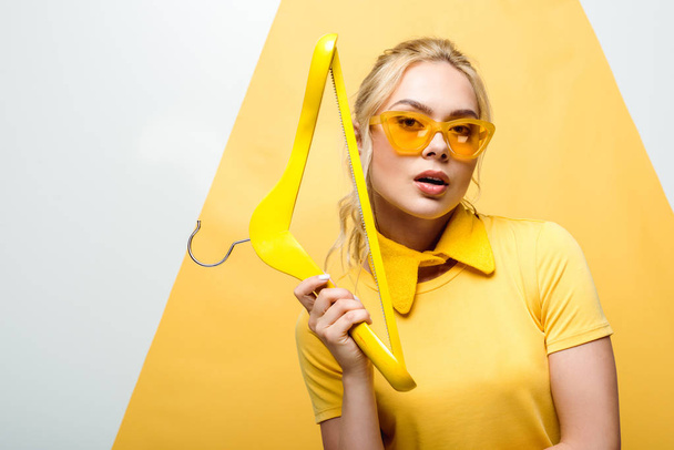 attractive blonde woman in sunglasses holding wooden hanger on white and yellow  - Valokuva, kuva
