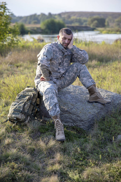 der Soldat sitzt und ruht. Trauriger Soldat. Müder Soldat. - Foto, Bild
