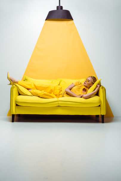 beautiful woman in sunglasses lying on sofa on white and yellow  - Foto, Bild