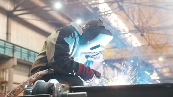 Construcción de plantas. Un trabajador hombre en un casco usando una máquina de soldadura en detalle de metal. El fuego brilla
 - Imágenes, Vídeo