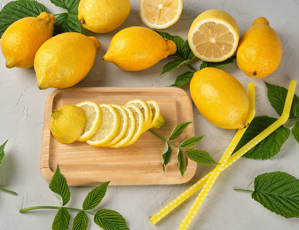 verse hele gele citroenen en gesneden vruchten - Foto, afbeelding