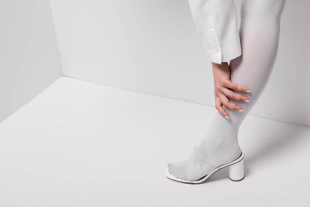 cropped view of stylish woman posing and touching leg on white - Fotografie, Obrázek
