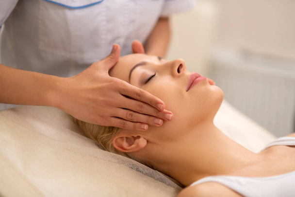 Beautiful woman enjoying face massage in beauty center - Fotó, kép