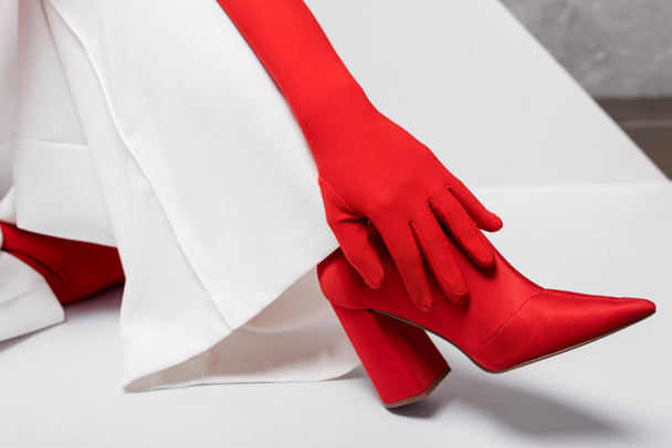cropped view of stylish young woman in red glove and shoe on white  - Foto, imagen