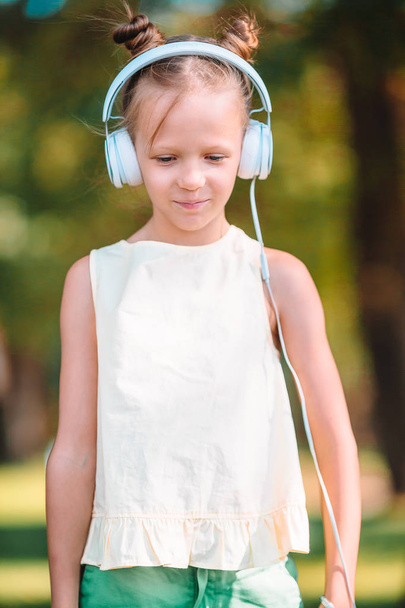 Little adorable girl listening music in the park - Fotoğraf, Görsel