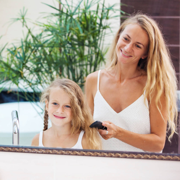 Mother combing daughter hair - 写真・画像