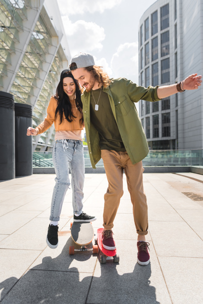 cheerful woman and man riding on skateboards - Fotó, kép