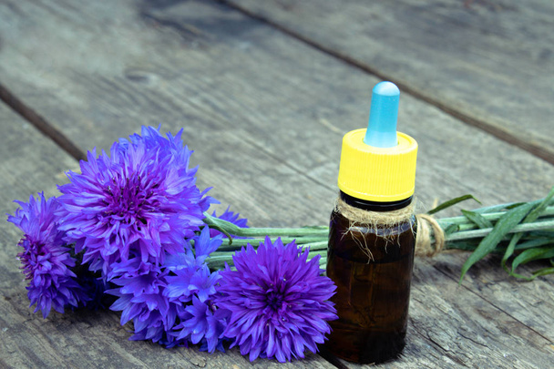 cornflower essential oil on a wooden background. - Photo, Image