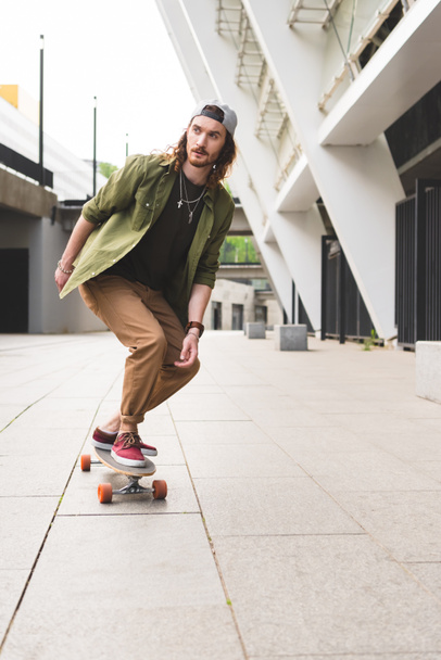 handsome man riding on skateboard in city, looking away - 写真・画像