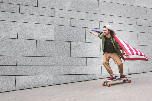 homem feliz no desgaste casual com bandeira americana montando no skate
 - Foto, Imagem