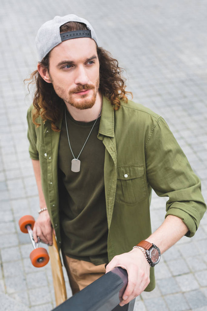high angle view of handsome man with skateboard looking away - Foto, Bild