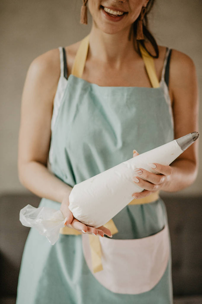 Beautiful woman in apron cooking dessert - Zdjęcie, obraz