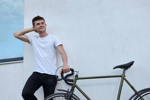 市内で自転車でポーズ ハンサムな流行に敏感な男. - 写真・画像