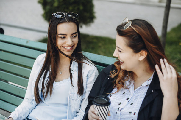 Duas mulheres caucasianas jovens falando sorrindo enquanto sentado em um ser
 - Foto, Imagem