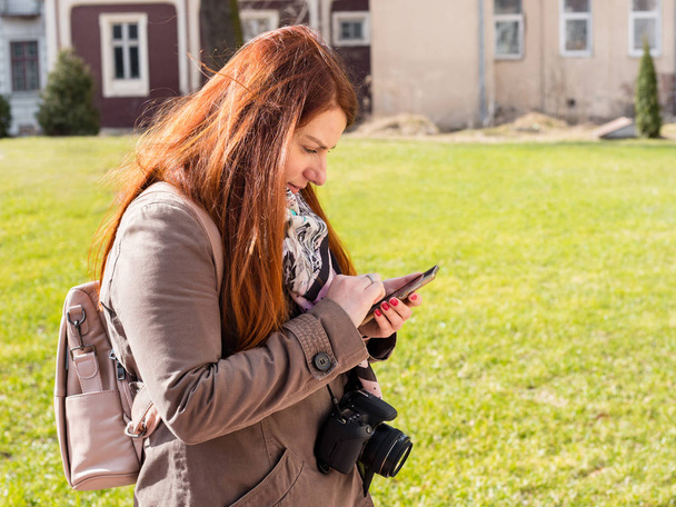 Красивая рыжая девушка видит смартфон в парке
 - Фото, изображение