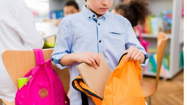 панорамний знімок дитини, що кладе книгу в помаранчевий рюкзак
   - Фото, зображення