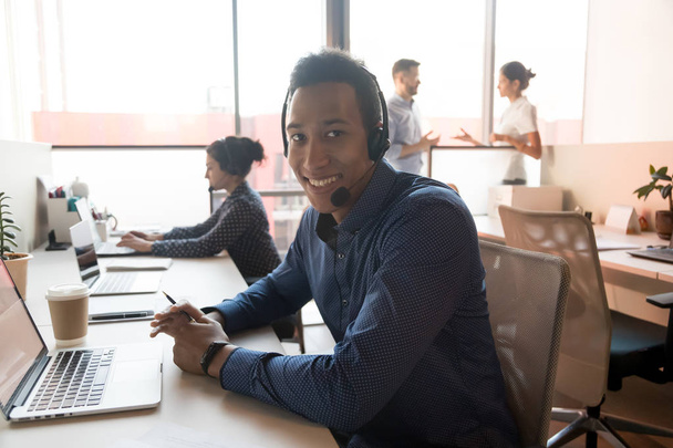 Portrait of smiling ethnic male agent in headset at workplace - Foto, Imagem