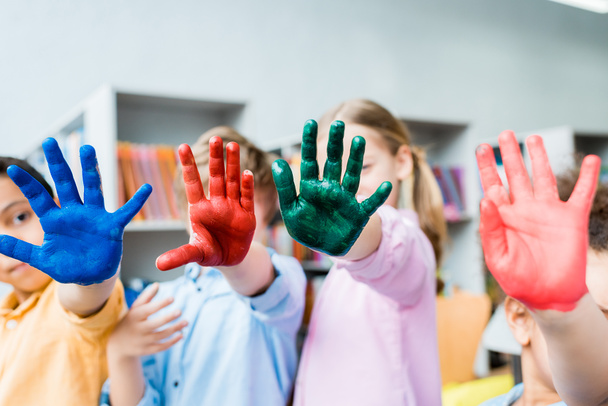 selective focus of multicultural kids covering faces with colorful hands  - Photo, image