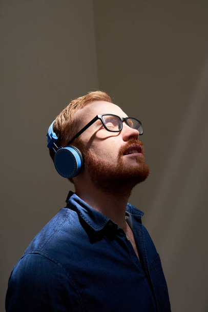 Young entrepreneur in glasses spending short break listening to music in headphones - Fotoğraf, Görsel