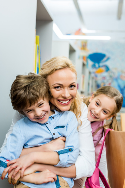 happy woman hugging cute and cheerful boy near smiling kid  - Photo, Image