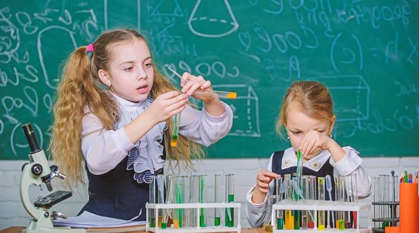 If at first you dont succeed try another experiment. Small school children holding test tubes for laboratory experiment. Little girls performing experiment in classroom. Demonstration and experiment - Photo, image