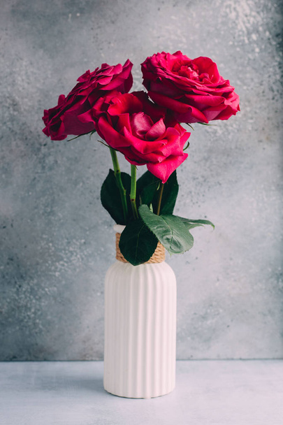 Dark pink roses in vase on grey background - 写真・画像