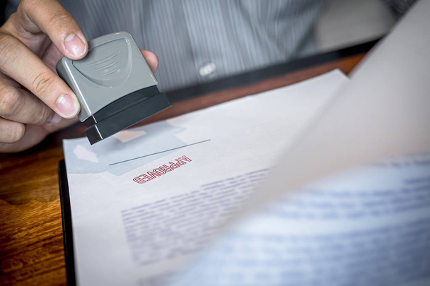 Руки бизнесмена штамп на бумажном документе для утверждения бизнеса
 - Фото, изображение