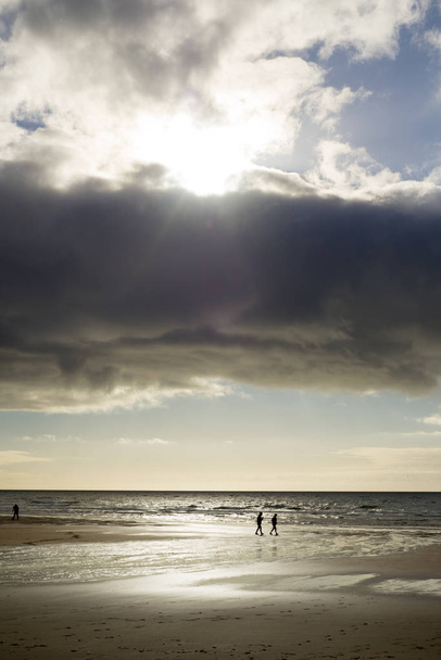silhouet van mensen die op het strand lopen - Foto, afbeelding