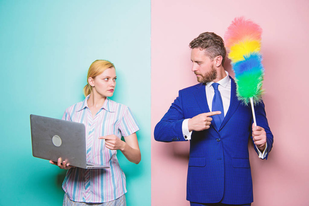 Changing their family roles. Family couple. Businessman and housewife. Husband stand with dust brush while wife holding laptop. Couple of handsome man and pretty woman. Housekeeping or business - Photo, image