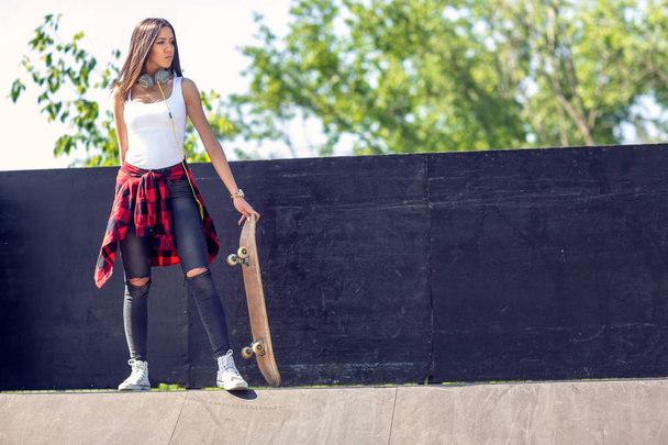 スケートボードを持つスポーティな十代の女の子。アウトドア、都会のライフスタイル - 写真・画像