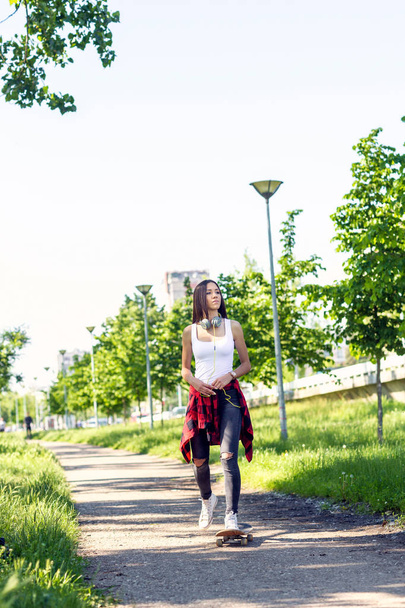 sporty girl riding skateboards on city street - Foto, afbeelding