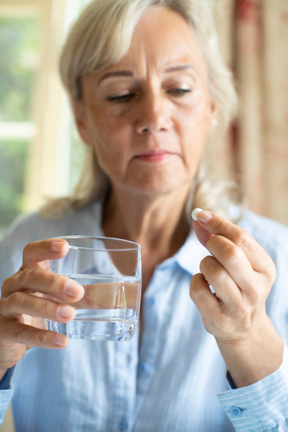 Senior Woman Taking Tablet With Glass Of Water At Home - Фото, зображення