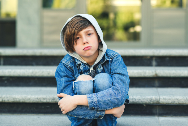 Üzgün çocuk okuldan önce merdivenlerde oturuyor. Şehir Caddesi 'nde yalnız mutsuz çocuk.  - Fotoğraf, Görsel