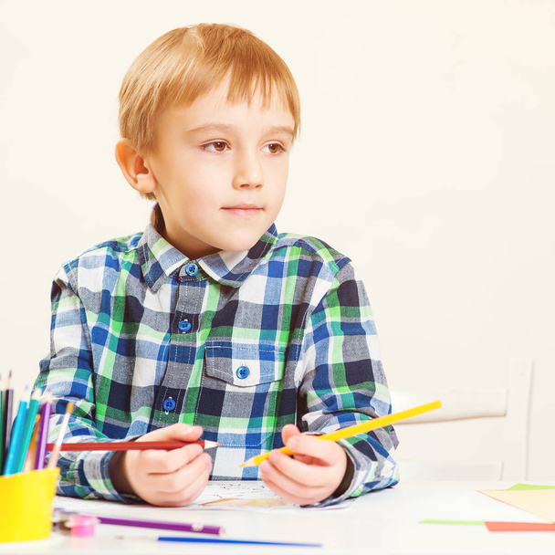 カラフルな鉛筆で描く幸せな小さな男の子。クラスでかわいい未就学児の絵。子供のためのアートクラス. - 写真・画像