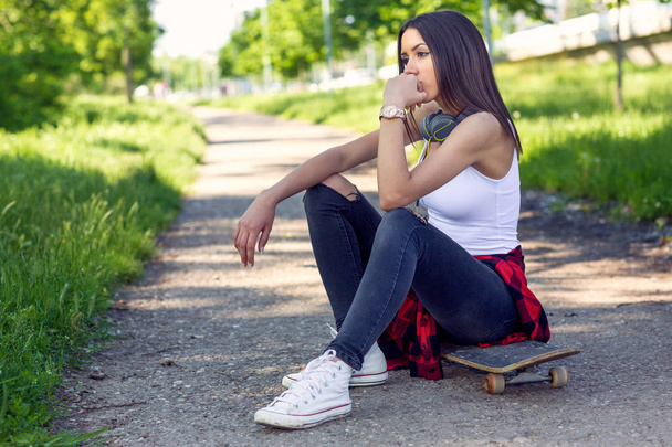 スケートボードに座っている女性。屋外での都市生活 - 写真・画像